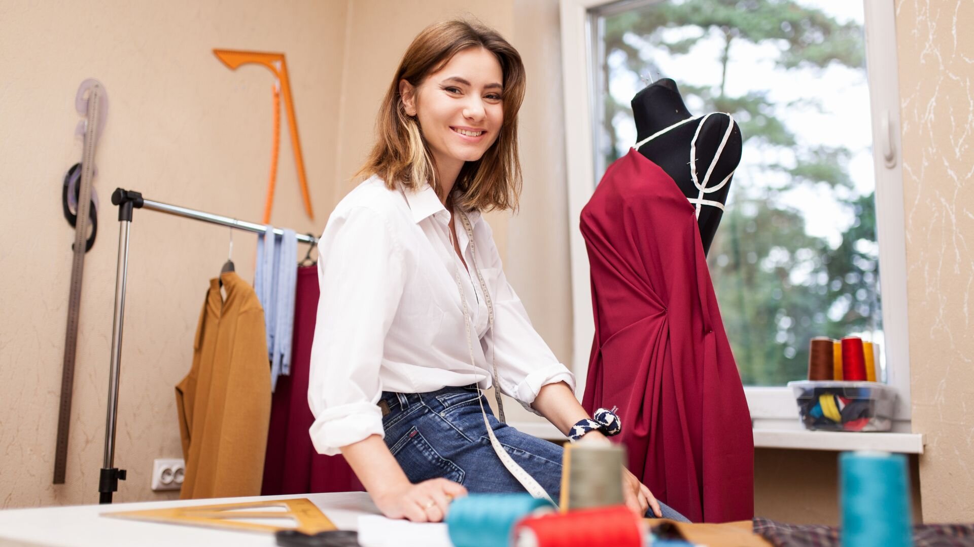 Giovane stilista donna con abiti sullo sfondo